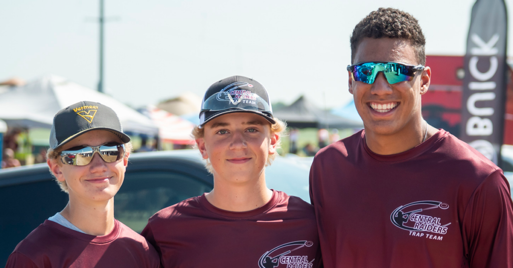 Three young men in maroon shirts standing next to each other.